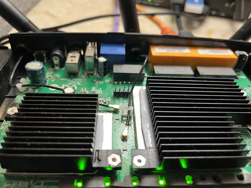 Photo of the top of a TP-Link Archer C59 AC1350 circuit board. In the middle of the photo four header pins have been soldered to the board